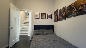 Une chambre à coucher avec un lit, un escalier et trois tableaux encadrés accrochés au mur.