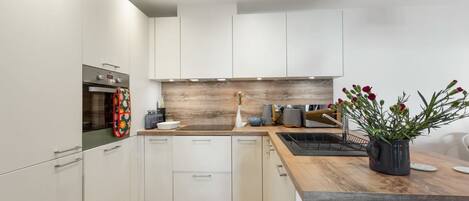 A modern kitchen with white cabinets, a wooden countertop, and a built-in oven.