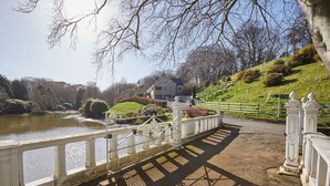 A bridge with white railings leading to a house by a lake. - Host Stay The Lakehouse (Whitby)