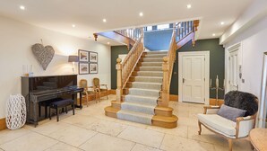 A spacious living room with a grand staircase, a piano, and a cozy seating area. - Host Stay The Lakehouse (Whitby)