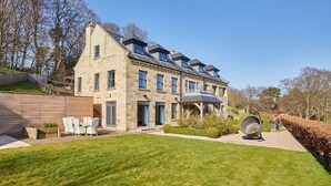 A stone house with a large garden, a covered patio, and a lawn. - Host Stay The Lakehouse (Whitby)