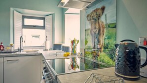 Eine moderne Küche mit einem großen Fenster, einem Wasserkocher und Blick auf einen Löwen durch eine Glaswand.