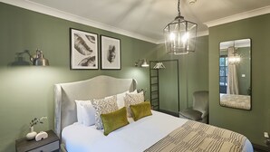 Une chambre à coucher comprenant un lit, une table de chevet, un miroir et un luminaire suspendu.