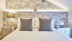 Ett sovrum med en säng, två sängbord, en lampa och en väggmonterad lamparmatur.