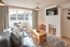 Relax in this inviting living room with a comfortable sofa, fireplace, and large windows offering views of the outdoors.