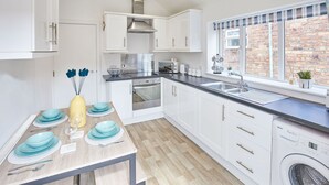 Una cocina moderna con gabinetes blancos, una campana extractora de acero inoxidable, horno empotrado y lavavajillas.