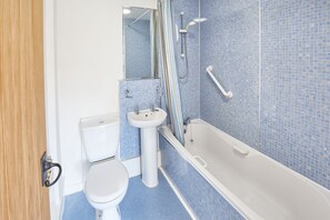 Bathroom features a pedestal sink, bathtub, and showerhead, set against a backdrop of blue mosaic tiles.