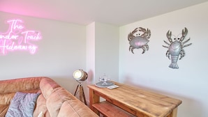 Een gezellige zithoek met een roze bank, een houten salontafel en wanddecoratie.