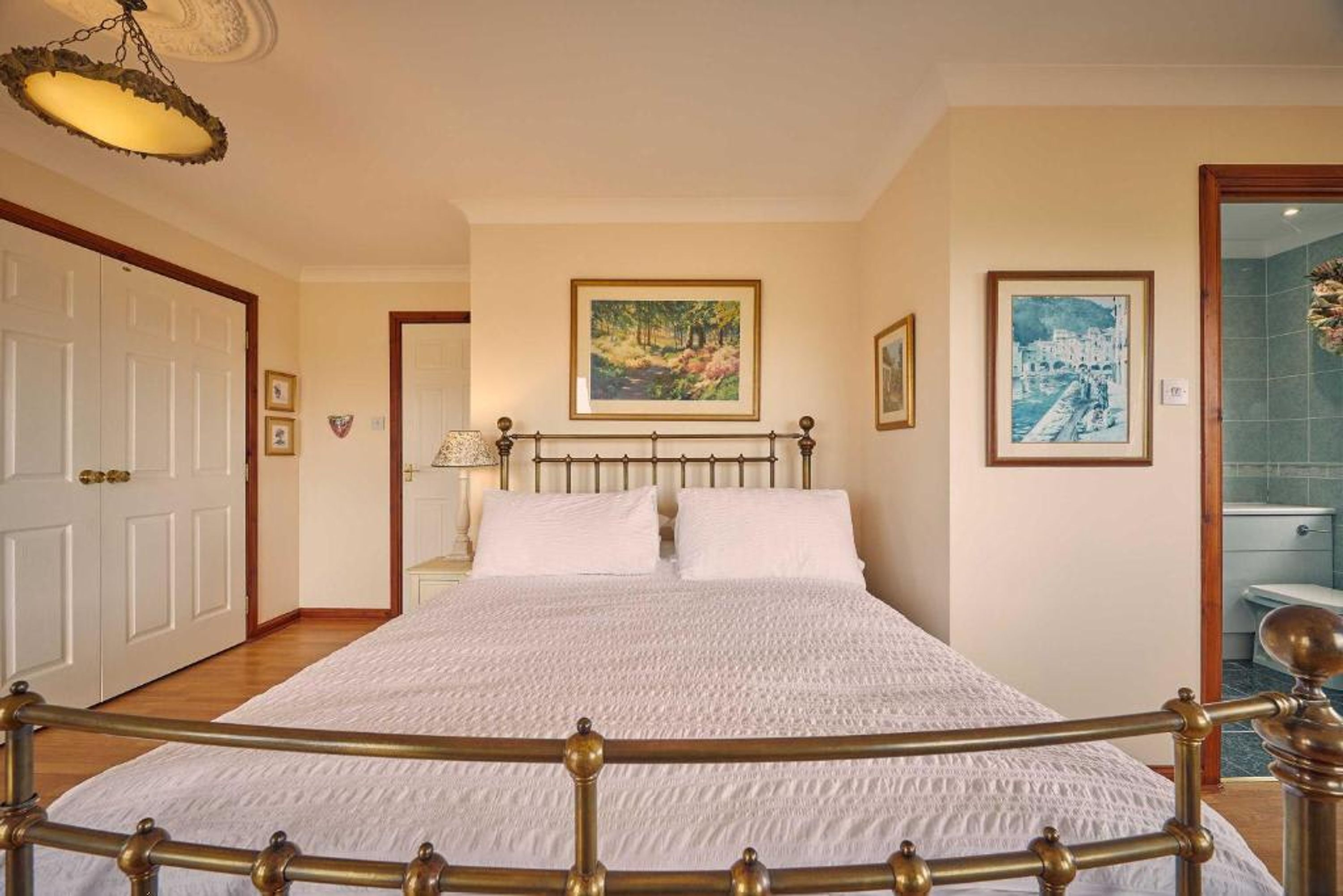 Une chambre à coucher avec un grand lit, une tête de lit en bois et un luminaire suspendu.