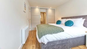 A bedroom with a bed, a grey headboard, and a green throw blanket. - Host Stay Ocean Pearl (Seahouses)