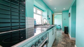Uma cozinha moderna com fogão preto, armários brancos e painel de azulejos.