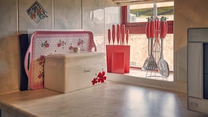 A kitchen counter with a bread box, a knife holder, and a window with a view of the outdoors. - Host Stay No 3 Rose Cottage (Belford)
