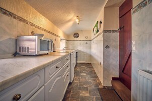 Cocina con microondas, armarios y salpicadero de azulejos.