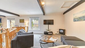 A modern living room with a fireplace, a flat-screen TV, and a dining area with a table and chairs. - Host Stay The Burrow (Alnwick)
