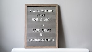 A framed sign with text directing to book a stay at Host & Stay. - Host Stay The Bach (Chathill)