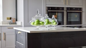 Eine Küche mit schwarzem Arbeitsplatz, zwei Gläsern mit grünen Äpfeln und modernen Geräten.