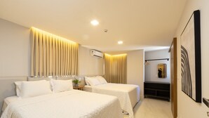 A hotel room with two beds, a bedside table with a plant, an air conditioning unit, and a mirror on the wall. - Qavi - Gaudium Apart Hotel (João Pessoa)