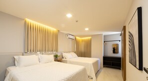 A hotel room with two beds, a bedside table, an air conditioning unit, a mirror, and a painting on the wall. - Qavi - Gaudium Apart Hotel (João Pessoa)