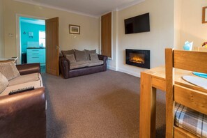 A living room with a brown leather sofa, a wooden dining table, and a fireplace. - Host Stay No 5 Poppy Cottage (Belford)