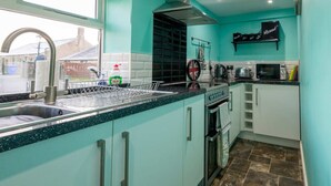 Una cocina moderna con armarios color turquesa, un lavamanos de acero inoxidable, un horno empotrado y un microondas.