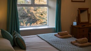 Una habitación de hotel con una cama, una ventana con cortinas, un aparador y un espejo.