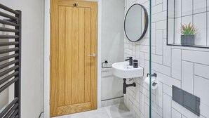 A bathroom with a wooden door, a white sink with a mirror above it, and a potted plant on the wall. - Host Stay Anchor Apartment North Marine House (Scarborough)