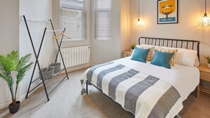 A bedroom with a bed, bedside tables, a radiator, a drying rack, and a potted plant. - Host Stay Anchor Apartment North Marine House (Scarborough)