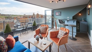 A modern apartment with a balcony, furnished with orange chairs and a blue sofa, a small bar area, and a telescope. - Host Stay Devereux House (Whitby)