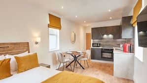 A hotel room with a bed, a dining table with chairs, a kitchen area, and a large mirror. - Host Stay Studio Pod 3 (Saltburn-by-the-Sea)