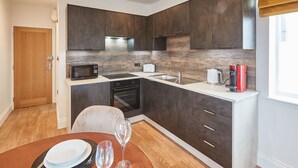A compact kitchen with dark cabinets, a microwave, a toaster, a coffee maker, and a sink. - Host Stay Studio Pod 3 (Saltburn-by-the-Sea)