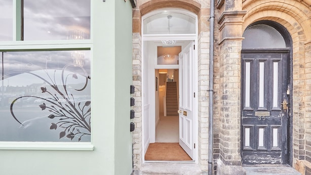 A narrow entrance with a white door and a black door, leading to a staircase. - Host Stay Studio Pod 3 (Saltburn-by-the-Sea)