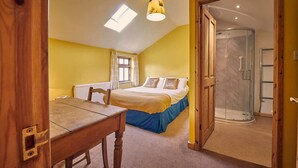 A bedroom with a bed, a table, a window, and a shower area. - Host Stay The Red Brick Barn (Bishop Auckland)