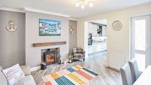 A modern living room with a fireplace, a colorful rug, and nautical decor. - Host Stay 1 Montrose Street (Saltburn-by-the-Sea)
