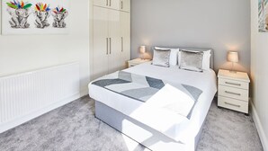 A bedroom with a bed, two bedside tables, a wardrobe, and a painting on the wall. - Host Stay 1 Montrose Street (Saltburn-by-the-Sea)