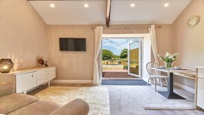 A modern bedroom with a large window, a flat-screen TV, a desk, and a sofa. - Host Stay The Pepper Pot (Alnwick)