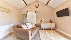 A cozy room with a brown sofa, a white dresser, a fluffy rug, and a mounted TV. - Host Stay The Pepper Pot (Alnwick)