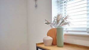 A wooden table with a vase of dried flowers and a textured object. - Host Stay Sandcastles Apartment (Whitby)