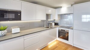 A modern kitchen with white cabinetry, a Bosch microwave, a toaster, and a sink. - Host Stay Sandcastles Apartment (Whitby)