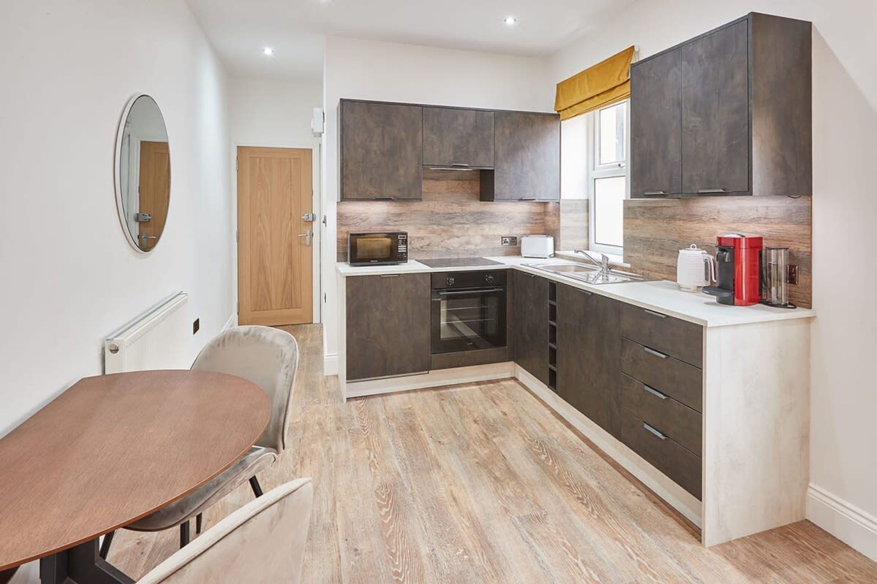 A compact kitchen with dark cabinets, a microwave, a toaster, and a coffee maker.