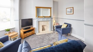 A living room with a fireplace, a television, and two sofas. - Host Stay Cobblestones (Redcar)