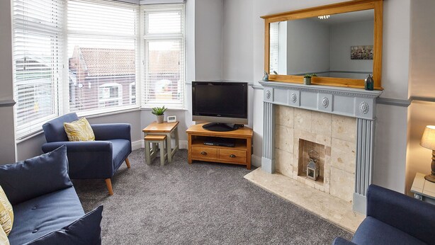 A living room with a fireplace, a television, and a sofa. - Host Stay Cobblestones (Redcar)