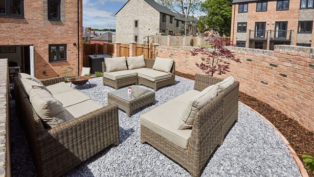 A patio area with wicker furniture and a gravel floor.