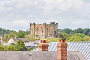 A castle-like building with multiple windows and a prominent tower, surrounded by greenery and residential buildings. - Host Stay Castle View (Durham)