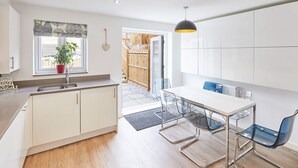 A modern kitchen with white cabinets, a sink, and a dining area with a table and chairs.