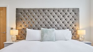 A bed with a tufted headboard, white bedding, and two bedside lamps.