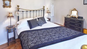 A bedroom with a bed, a dresser, a mirror, and a lamp. - Host Stay Honeysuckle Cottage (Saltburn-by-the-Sea)