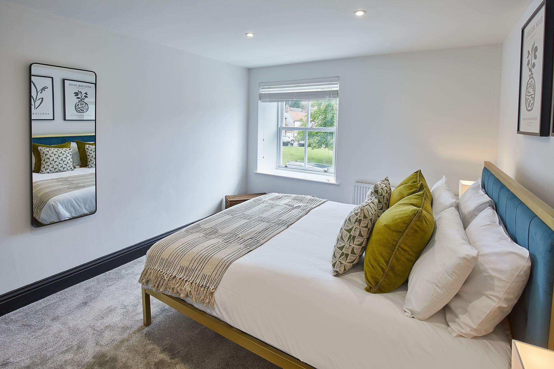 A modern bedroom with a bed, a window, and a mirror.