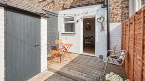 A small backyard with a wooden deck, a grey door, and a white wall. - Host Stay The Railman s House (York)