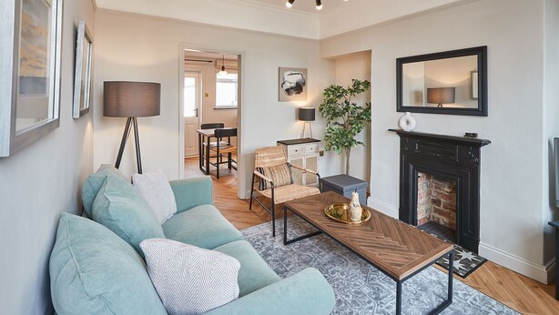 A living room with a sofa, coffee table, fireplace, and a dining area in the background. - Host Stay The Railman s House (York)