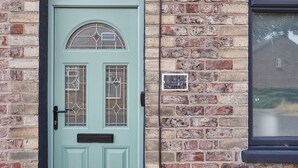 A teal door with a glass window, a mailbox, and a brick wall with a small plaque. - Host Stay The Railman s House (York)